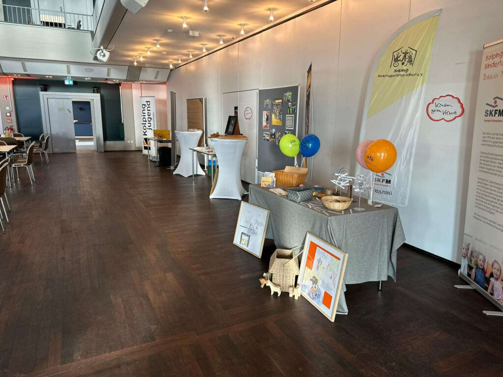 Foto Diözesanversammlung Diözesanverband Kolping Köln, Im hinteren Bereich wurden Infostände aufgebaut. Hierunter auch ein Stand der Kolping-Kindertagesstätten Velbert e.V.